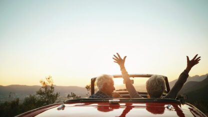 Older individuals relaxing in a convertible car with the top down.