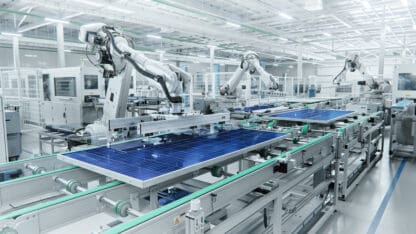 Robotic arms working on an automated production line at a photovoltaic plant.