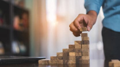 Person stalking wooden blocks into a rising staircase.