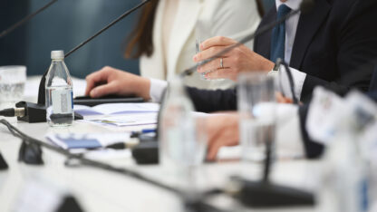 Speakers sitting in front of microphones at a conference table.