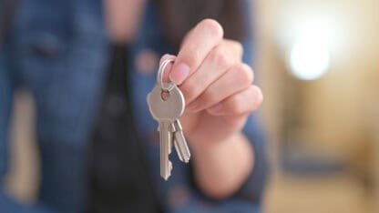Woman handing over a pair of keys on a keyring.