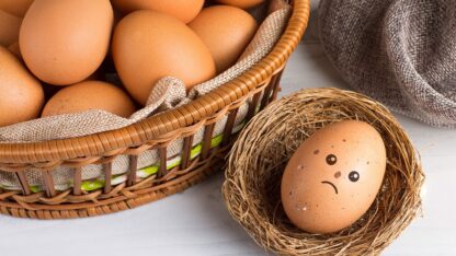 Basket of brown eggs with a single speckled egg removed to the side with an unhappy expression drawn on it.