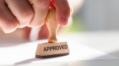 Person using a rubber stamp labeled with the word APPROVED.