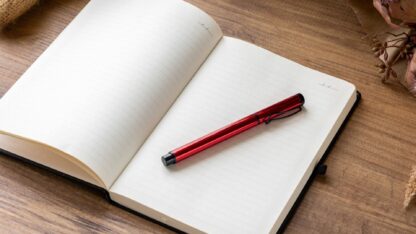 Open notebook with red pen on wooden desk, symbolizing professional financial planning and consulting services offered by MGO CPA.