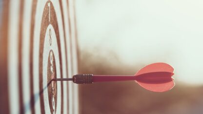 Dart embedded in dartboard's bullseye mark.
