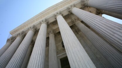 Upward perspective of the columns at a building's entrance.
