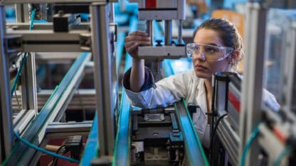 Woman inspecting automated production line equipment.