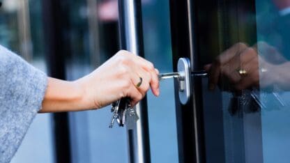 Person locking a glass door with a key.