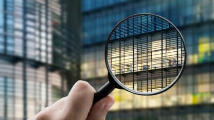 image of a magnifying glass behind held up to an office building.