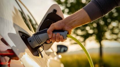 Man inserts a power cord into an electric vehicle (EV) for charging