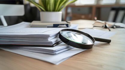 Neatly organized stack of documents with a magnifying glass on top