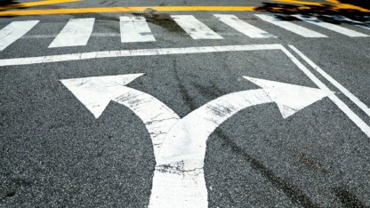 Arrow symbol point two separate directions on a street symbolizing the strategic choice between opting for 100% or 40% bonus depreciation