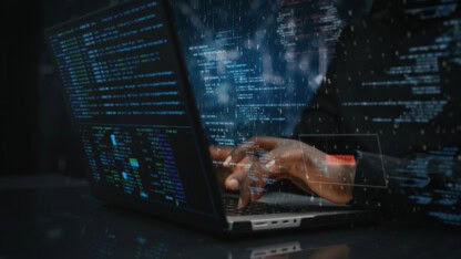 Hands of male sitting in front of computer, writing on keyboard focused on hacking
