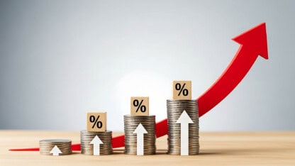 Image of increasing large stacks of coins with red upward arrow behind them representing increasing capex