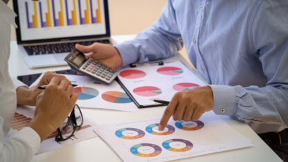 Man with calculator in hand pointing to pie charts