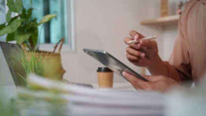 A person taking notes on a tablet computer at a desk